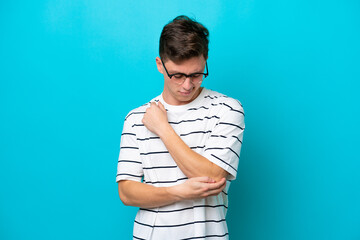 Wall Mural - Young handsome Brazilian man isolated on blue background with pain in elbow