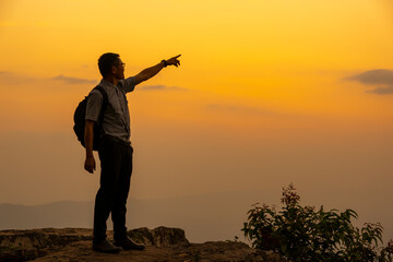 Man tourist on the cliff of the mountain on sunset background