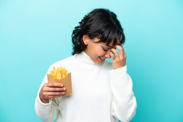 Wall Mural - Young Argentinian woman holding fried chips isolated on blue background laughing