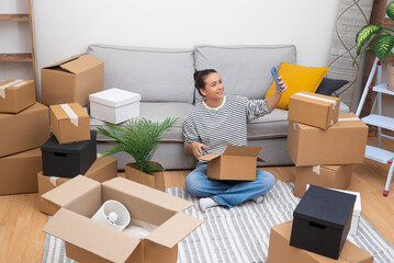 Aufkleber - Woman makes selfies with gearboxes around near couch in house waiting for boyfriend from office to help unpack things needed to decorate contemporary apartment