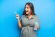 © luismolinero - Pregnant woman on blue background intending to realizes the solution while lifting a finger up
