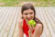 © luismolinero - Young pretty woman at outdoors holding an apple with happy expression