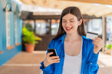 Wall Mural - Young pretty woman at outdoors buying with the mobile with a credit card