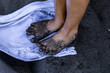 Woman's feet on a towel dirty with volcanic black sand from the beach