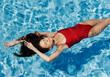 © SHOTPRIME STUDIO - Young woman in the pool in red swimsuit with a beautiful smile lying on the water and swimming in the blue pool in the sun, the concept of relaxing on vacation.
