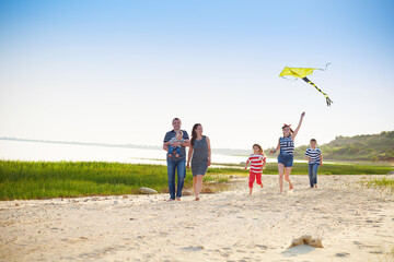 Wall Mural - Happy young family with flying a kite on the beach