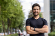 © Tetiana - Close-up portrait of a confident young male sportsman standing outside with his arms folded across his chest and smiling at the camera