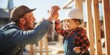 Father with toddler son building wooden house