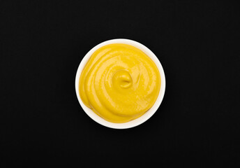 White bowl of yellow American mustard on table