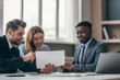 © gstockstudio - Smiling young couple sitting at office desk and examining papers while visiting financial advisor