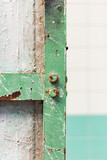 Fototapeta Na ścianę - Detail of a pillar with a green steel frame affected by rust in an old abandoned factory.