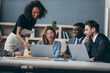 © gstockstudio - Smiling group of business people discussing strategy during team meeting at the office desk together