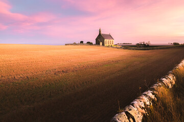 Wall Mural - The lone chapel Boarhills Church during a colourful sunset or sunrise in the rural countryside farmland of East Neuk, Fife, Scotland, UK.