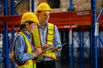 Wall Mural - engineers taking notes using tablets in a large industrial warehouse. Workers in safety clothing inspect equipment in warehouses for authenticity, manufacturing and export industry concepts.