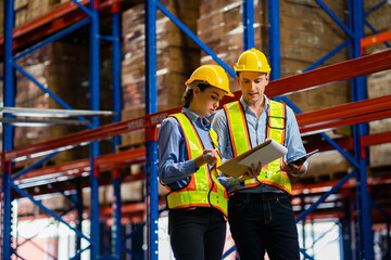 Wall Mural - engineers taking notes using tablets in a large industrial warehouse. Workers in safety clothing inspect equipment in warehouses for authenticity, manufacturing and export industry concepts.