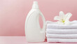 Plastic liquid detergent bottle and white towels. Fabric softener. Regular washing, laundry concept on pink background with copy space