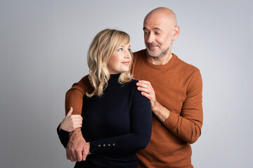 Mid aged couple couple embracing each other against isolated grey background