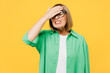 Elderly sad blonde woman 50s years old wear green shirt glasses casual clothes put hand on face facepalm epic fail mistaken omg gesture isolated on plain yellow background studio. Lifestyle concept.