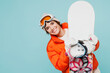 Young smiling woman wear warm padded windbreaker jacket hat ski goggles mask gloves hold snowboard look camera travel rest spend weekend winter season in mountains isolated on plain blue background.