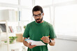 © Prostock-studio - Concentrated man with glasses and a beard, wearing a green t-shirt