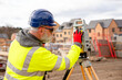 © Iryna - Surveyor builder site engineer with theodolite total station at construction site outdoors during surveying work