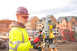 © Iryna - Surveyor builder site engineer with theodolite total station at construction site outdoors during surveying work