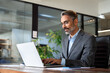 © Stock 4 You - Mature Indian or Latin business man ceo trader using computer, typing, working in modern office, doing online data market analysis, thinking planning tech strategy looking at laptop with copy space.
