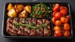 Food in a black divided catering plastic box, black clean background, top view, steak and vegetables meal. food photography