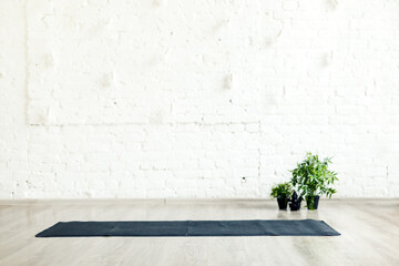 Unrolled yoga mat laid on the floor in empty space with white brick wall background