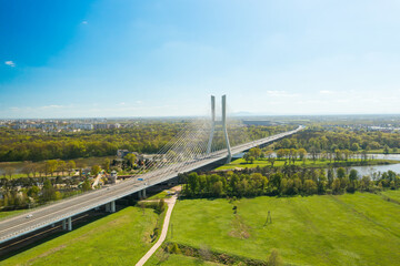 Wall Mural - Famous cable-stayed Redzinski Bridge over blue flowing river among lush green forests. Scenic nature and urban infrastructure near Wroclaw aerial view