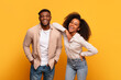 Cheerful young black couple laughing together against yellow background