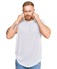 Wall Mural - Young irish man wearing casual clothes covering ears with fingers with annoyed expression for the noise of loud music. deaf concept.