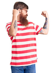 Sticker - Handsome young red head man with long beard wearing casual clothes showing arms muscles smiling proud. fitness concept.