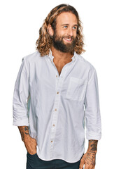 Wall Mural - Handsome man with beard and long hair wearing casual clothes looking away to side with smile on face, natural expression. laughing confident.