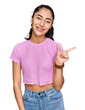 © Krakenimages.com - Hispanic teenager girl with dental braces wearing casual clothes with a big smile on face, pointing with hand finger to the side looking at the camera.