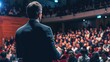 © PhilipSebastian - A speaker presenting to an audience in a conference hall, viewed from behind, focusing on public speaking and event hosting