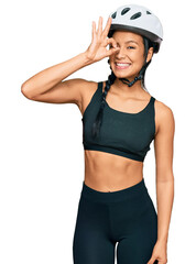 Wall Mural - Beautiful hispanic woman wearing bike helmet smiling happy doing ok sign with hand on eye looking through fingers