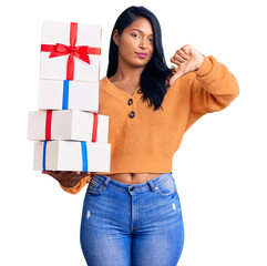 Poster - Hispanic woman with long hair holding gifts with angry face, negative sign showing dislike with thumbs down, rejection concept