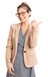 © Krakenimages.com - Beautiful caucasian woman with blonde hair wearing business jacket and glasses smiling with happy face looking and pointing to the side with thumb up.