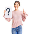 © Krakenimages.com - Beautiful caucasian woman with blonde hair holding question mark surprised with an idea or question pointing finger with happy face, number one