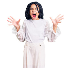 Sticker - Cute african american girl wearing casual white tshirt crazy and mad shouting and yelling with aggressive expression and arms raised. frustration concept.