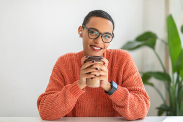 Cheerful calm millennial latin lady student manager enjoy peace and spare time, drink cup of coffee