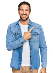 Sticker - Young handsome man wearing casual denim jacket cheerful with a smile of face pointing with hand and finger up to the side with happy and natural expression on face