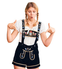 Wall Mural - Young beautiful blonde woman wearing oktoberfest dress pointing down with fingers showing advertisement, surprised face and open mouth