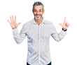 © Krakenimages.com - Middle age hispanic with grey hair wearing casual white shirt showing and pointing up with fingers number seven while smiling confident and happy.