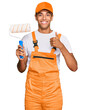 © Krakenimages.com - Young handsome african american man wearing cap and painter clothes holding painting roll smiling happy and positive, thumb up doing excellent and approval sign