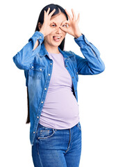 Poster - Young beautiful chinese woman pregnant expecting baby doing ok gesture like binoculars sticking tongue out, eyes looking through fingers. crazy expression.