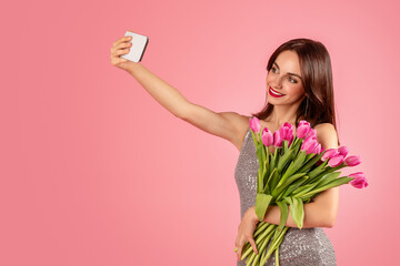 Wall Mural - Smiling woman in a sequined dress taking a selfie with her smartphone