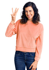 Wall Mural - Young beautiful hispanic woman wearing casual clothes showing and pointing up with fingers number three while smiling confident and happy.