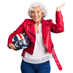 Canvas Print - Senior grey-haired woman holding motorcycle helmet celebrating victory with happy smile and winner expression with raised hands